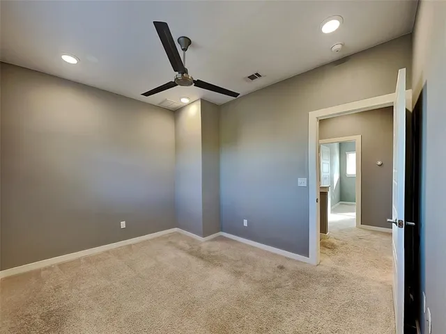 a view of a livingroom with a ceiling fan & windows