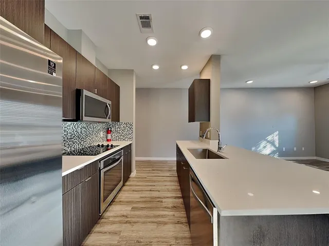 a kitchen with stainless steel appliances a sink and a refrigerator