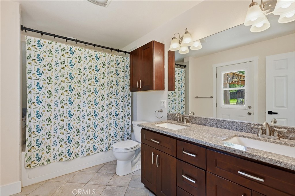16906 Greenridge Road Hidden Valley Lake, CA 95467 - Photo 9 of 24 a bathroom with a granite countertop sink a toilet a mirror a lamp and shower curtain