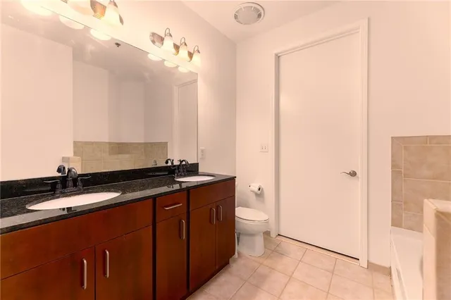 a bathroom with a granite countertop sink a toilet and a mirror