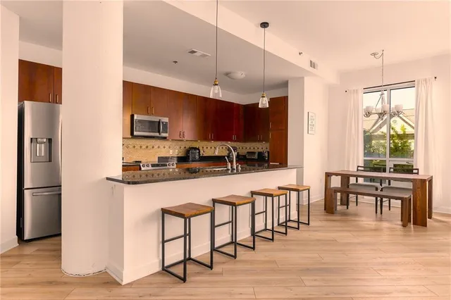 a open kitchen with stainless steel appliances granite countertop a stove refrigerator and a dining table