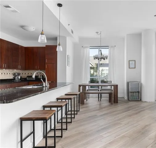 a kitchen with stainless steel appliances granite countertop a stove top oven a sink a dining table and chairs with wooden floor