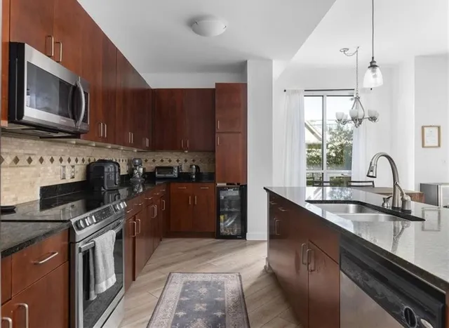 a kitchen with stainless steel appliances granite countertop a stove sink microwave and refrigerator