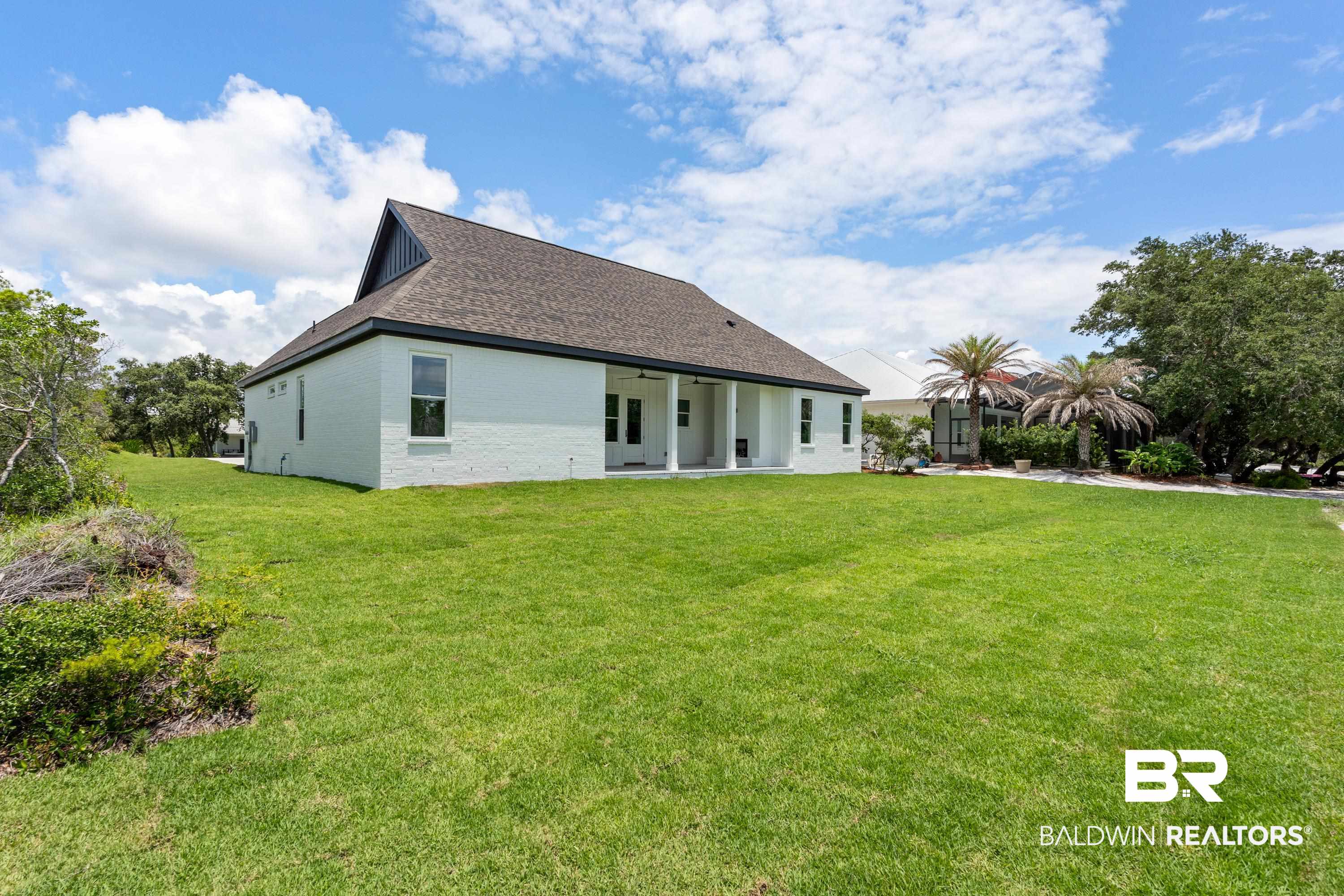 30650 Ono N Loop West Orange Beach, AL 36561 - Photo 36 of 38 Rear view of house with a lawn, a shingled roof, and brick siding