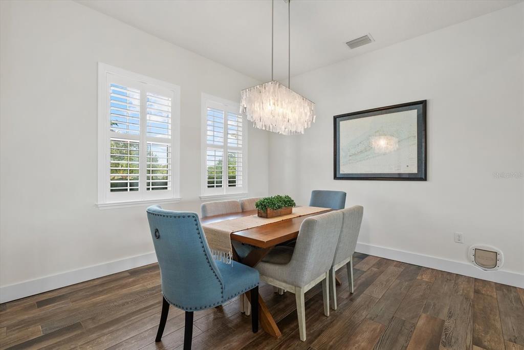 6816 Hawkins Road Sarasota, FL 34241 - Photo 9 of 60 a dining room with wooden floor and a chandelier