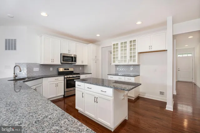 a kitchen with granite countertop a stove a sink and a refrigerator