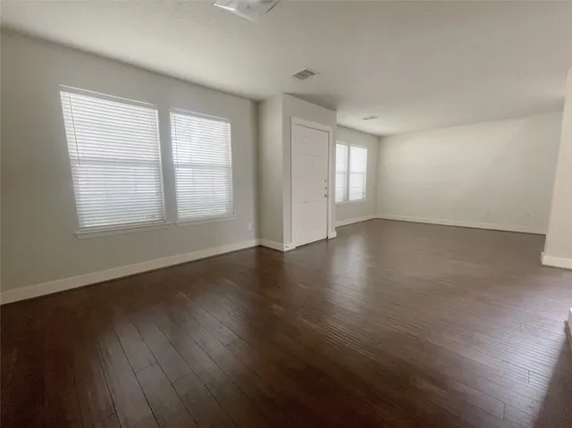 an empty room with wooden floor and windows