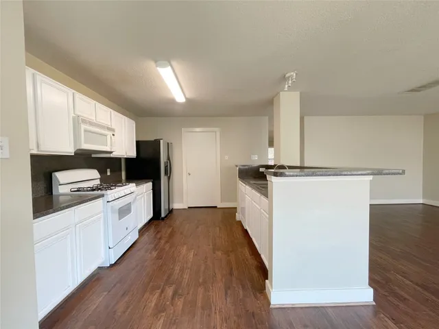 a kitchen with granite countertop a refrigerator stove top oven and sink