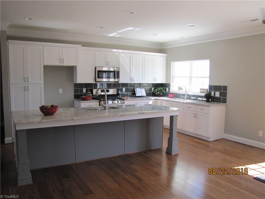 3609 Ruby Road Winston-Salem, NC 27106 - Photo 5 of 27 Large, Open Kitchen. White cabinets, beautiful granite counters and granite top island, tile backsplash, stainless steel built-in microwave, dishwasher & freestanding gas range/oven. There is a 2nd sink located on the Island.