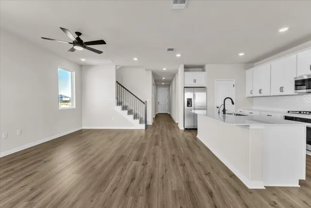 a view of a kitchen with wooden floor a sink a refrigerator and window