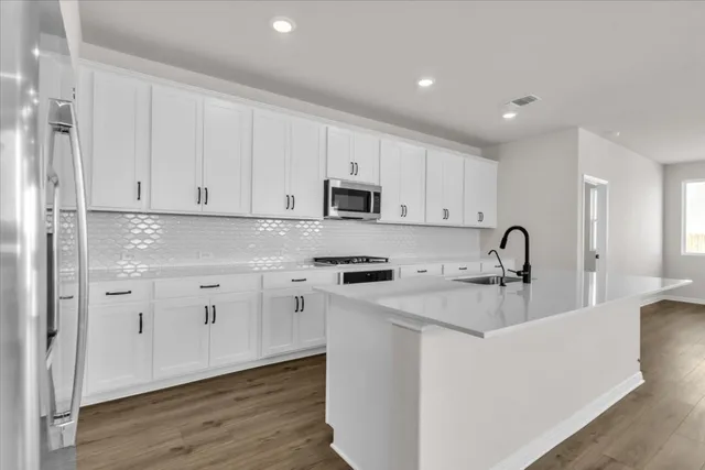 a kitchen with granite countertop white cabinets and stainless steel appliances