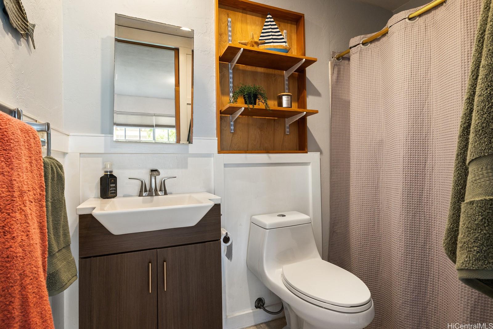 92-905 Hame Place, Unit 19203 Kapolei, HI 96707 - Photo 19 of 23 a bathroom with a sink a toilet and shower curtain