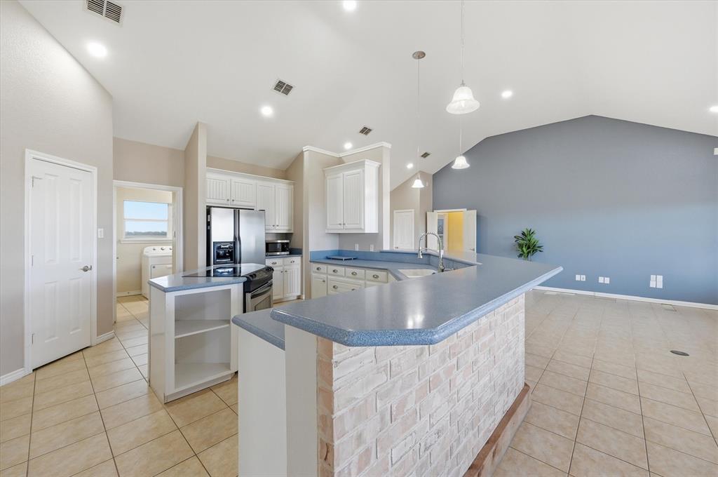1616 Nash-Howard Road Waxahachie, TX 75165 - Photo 13 of 36 a large kitchen with kitchen island a sink a counter and a view of living room