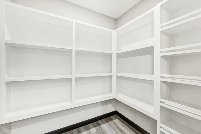 an empty room with wooden floor chandelier and windows