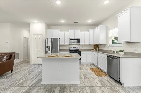 a kitchen with stainless steel appliances granite countertop a sink a stove a refrigerator and cabinets