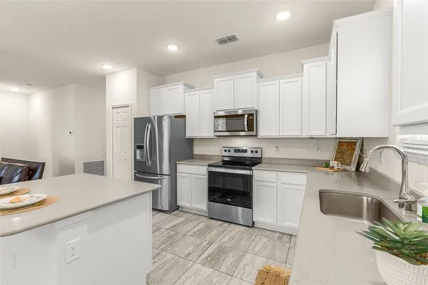 a kitchen with a sink a refrigerator a stove top oven and cabinetry