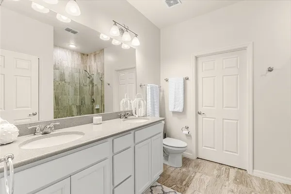 a spacious bathroom with a granite countertop sink a toilet and a large mirror