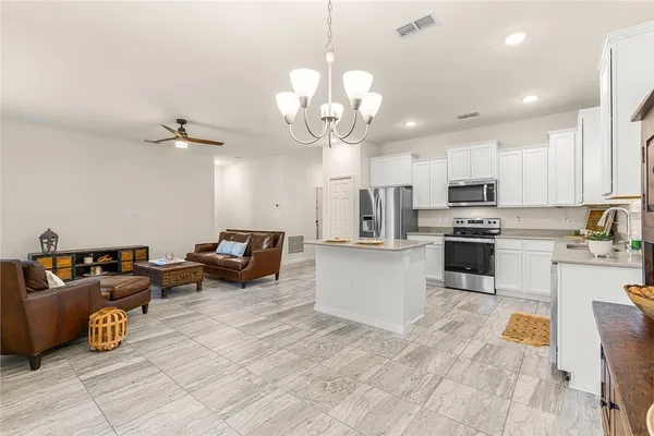 a kitchen with stainless steel appliances granite countertop a refrigerator a sink dishwasher a dining table and chairs with wooden floor