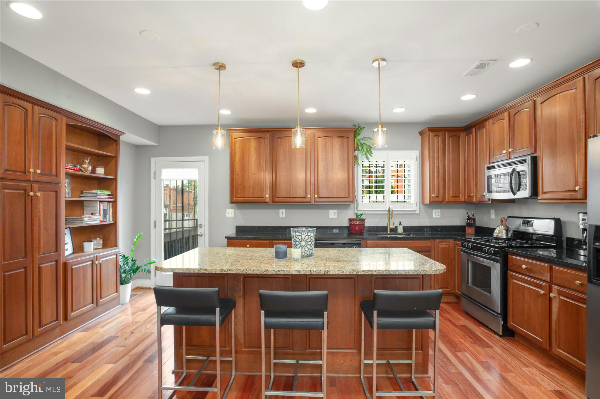 323 T Street Northwest Washington, DC 20001 - Photo 9 of 35 a kitchen with stainless steel appliances granite countertop a stove a sink a microwave a dining table and chairs with wooden floor