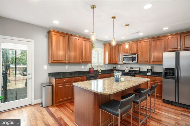 a kitchen with stainless steel appliances granite countertop a sink a stove a refrigerator cabinets and wooden floor
