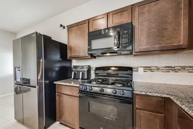 a kitchen with stainless steel appliances granite countertop a refrigerator stove and microwave