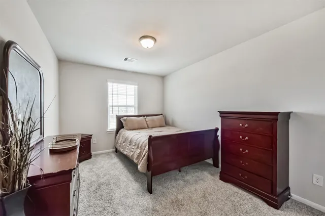 a bedroom with a bed and a dresser with mirror
