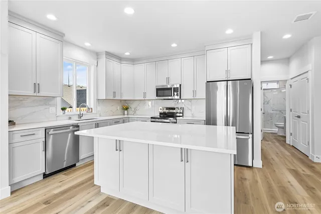 a kitchen with stainless steel appliances granite countertop a refrigerator sink and white cabinets