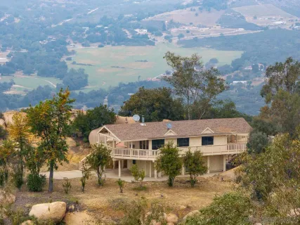 a front view of a house with a yard and mountain view in back