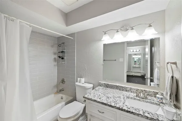 a bathroom with a granite countertop sink toilet and shower