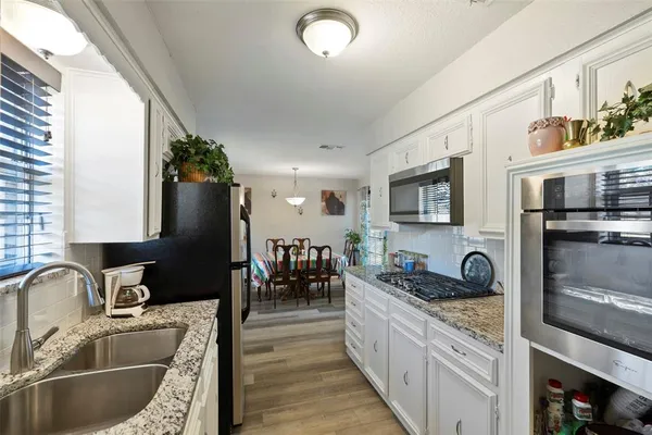 a kitchen with granite countertop a sink stove and refrigerator