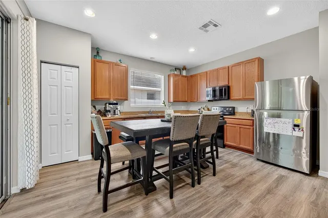 a kitchen with stainless steel appliances a dining table chairs refrigerator and microwave