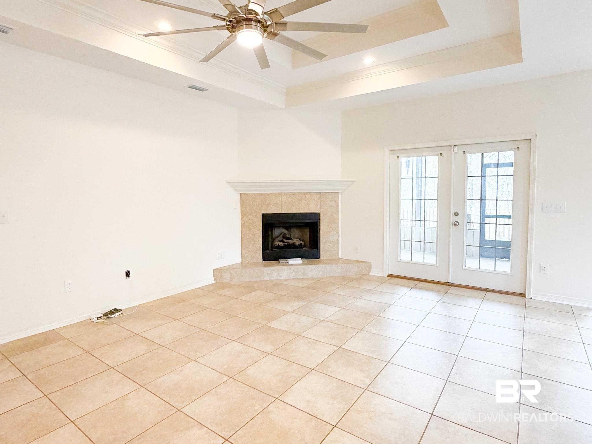 7332 Raintree Lane Gulf Shores, AL 36542 - Photo 4 of 21 Unfurnished living room featuring a ceiling fan, french doors, light tile patterned flooring, crown molding, and a tile fireplace
