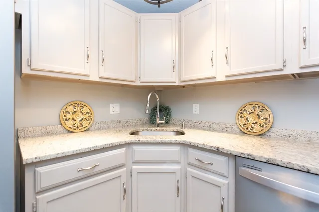 a kitchen with granite countertop white cabinets and a sink