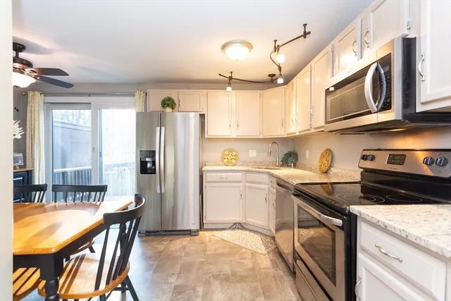 a kitchen with stainless steel appliances granite countertop a sink a stove a refrigerator cabinets and dining table
