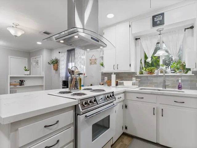 a kitchen with stainless steel appliances white cabinets a sink a stove a refrigerator and a window