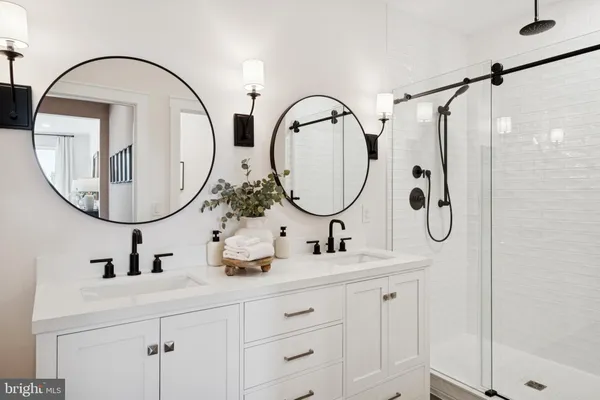 a bathroom with a double vanity sink mirror and glass door