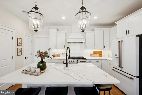 a kitchen with kitchen island a stove a chandelier and a dining table