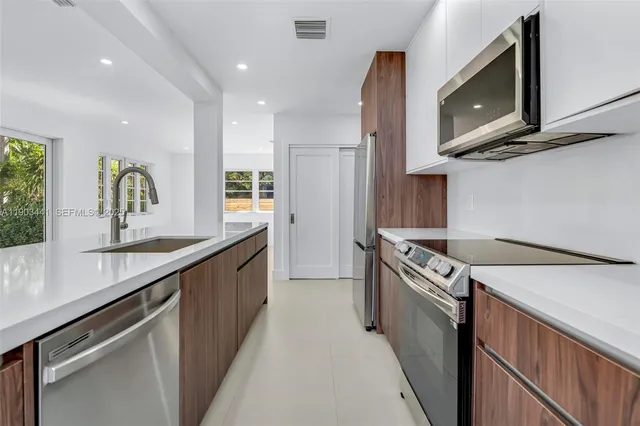 a kitchen with stainless steel appliances granite countertop a sink a stove top oven a counter space and cabinets