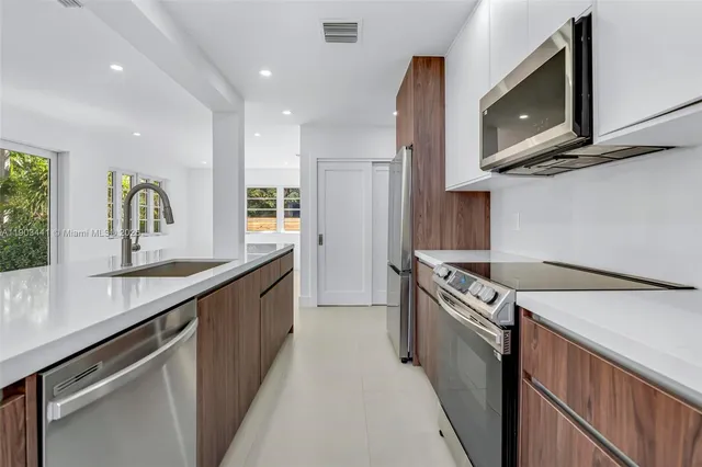 a kitchen with stainless steel appliances granite countertop a sink a stove top oven a counter space and cabinets