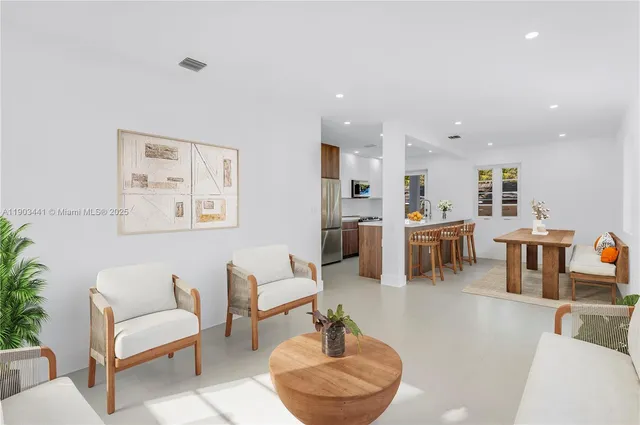 a living room with furniture and a view of kitchen