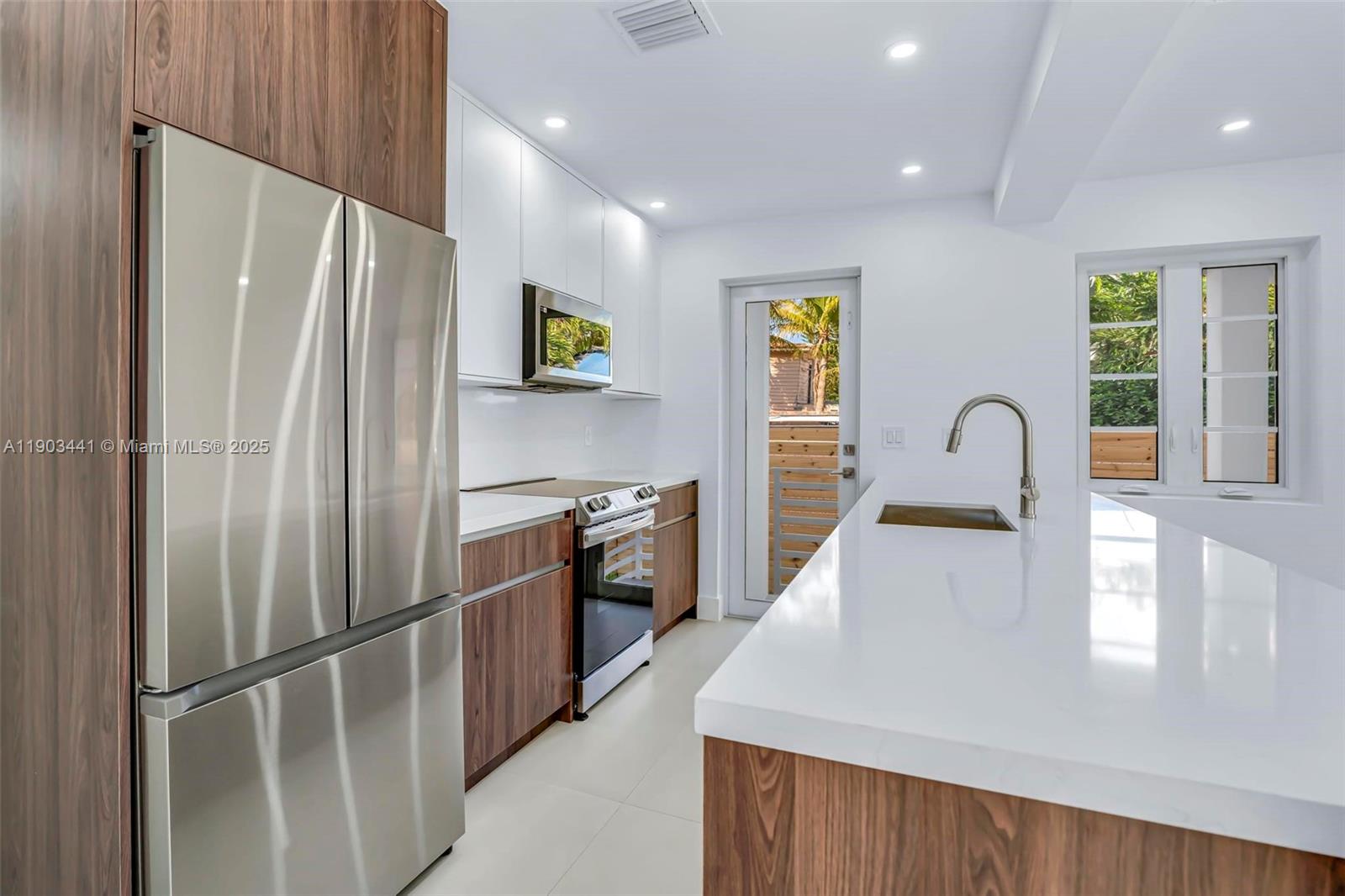 524 Northeast 65th Street, Unit 1 Miami, FL 33138 - Photo 10 of 26 a kitchen with stainless steel appliances granite countertop a refrigerator a sink a stove and a refrigerator with wooden floor