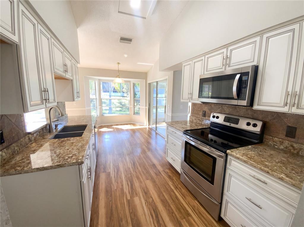 7410 Willowbrook Drive Spring Hill, FL 34606 - Photo 6 of 23 a kitchen with granite countertop wooden floors appliances and window
