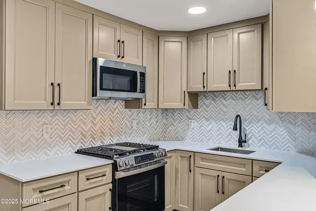 a kitchen with granite countertop white cabinets and stainless steel appliances