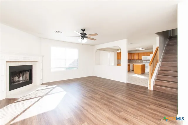 a view of an empty room with wooden floor fireplace and a window