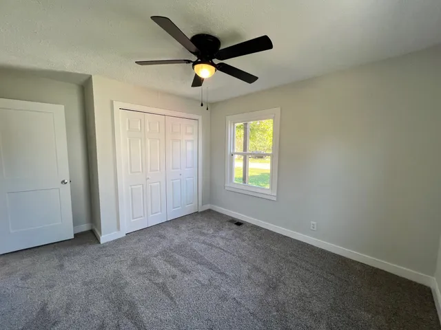 an empty room with ceiling fan and windows