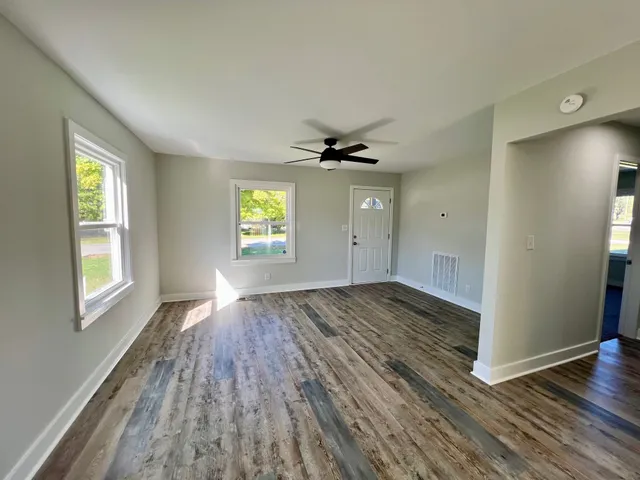 an empty room with wooden floor and windows