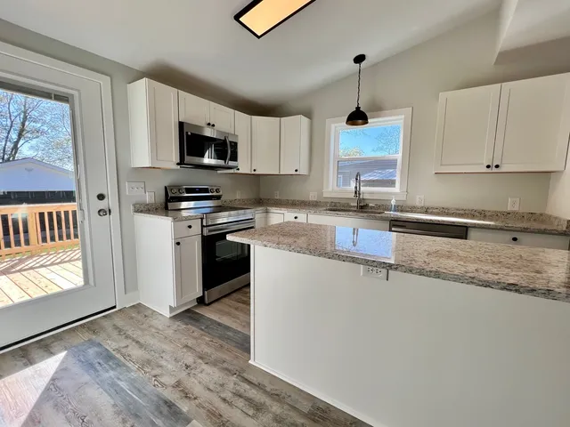 a kitchen with granite countertop cabinets stainless steel appliances a sink and a window