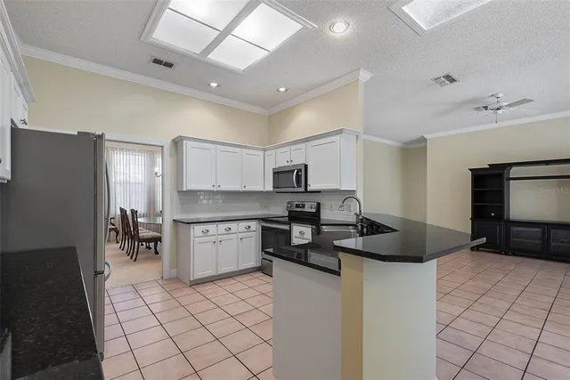 a kitchen with stainless steel appliances granite countertop a refrigerator and white cabinets