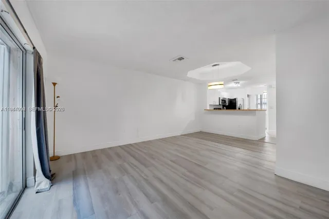 a view of empty room with wooden floor and window