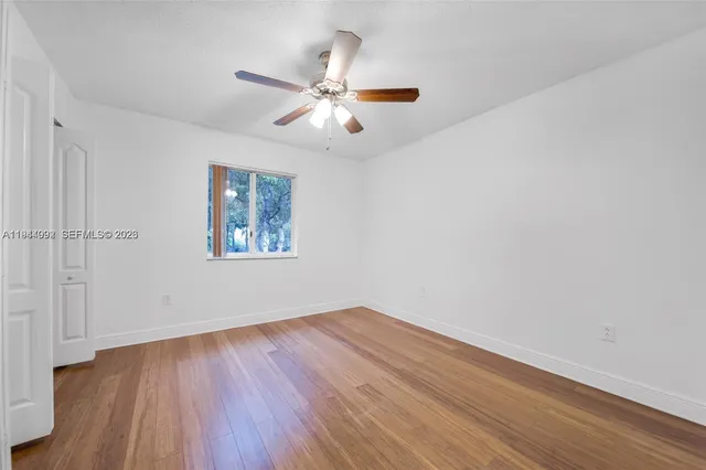 an empty room with wooden floor closet and fan